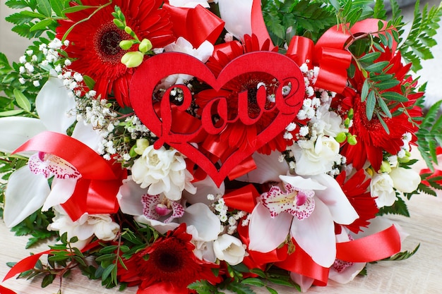 Photo bouquet d'orchidées blanches de gerberas rouges et freesias et le mot amour