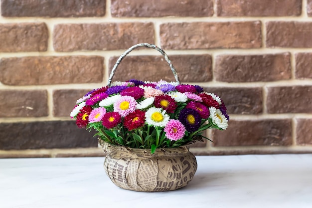 Bouquet de petits chrysanthèmes en forme de panier Bouquet sur un tableau blanc contre un mur de briques