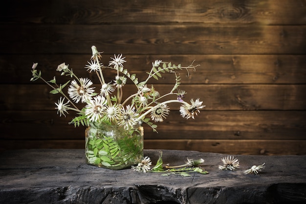 Bouquet de pissenlits dans un bocal en verre sur fond de bois foncé