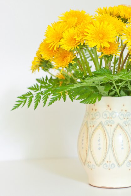 Bouquet de pissenlits dans une cruche blanche