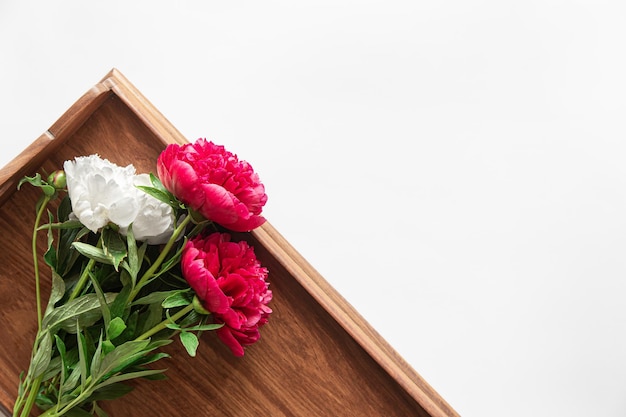 Bouquet de pivoine sur un plateau en bois sur un plat blanc