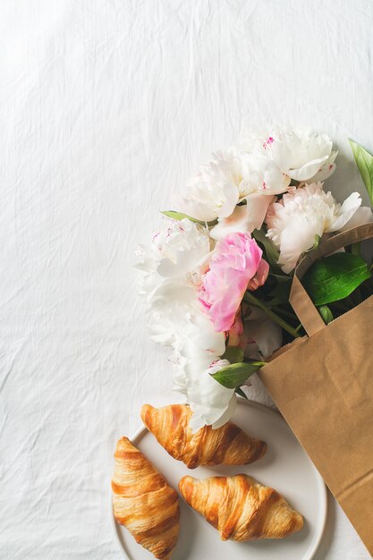 Bouquet de pivoines dans un sac en papier et croissants