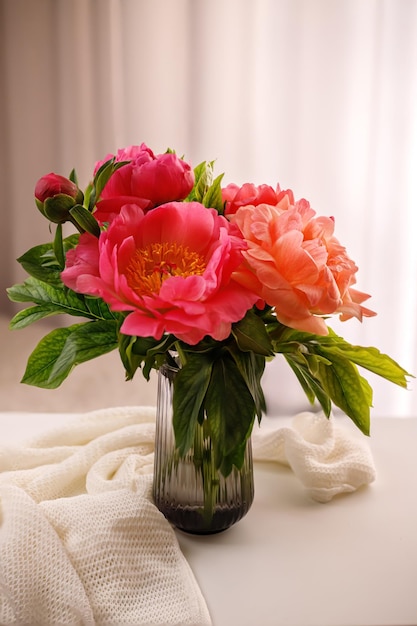 Bouquet de pivoines en fleurs fraîches dans un vase en verre dans la pièce sur la table