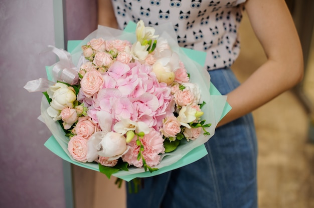Bouquet de pivoines roses dans les mains de la femme