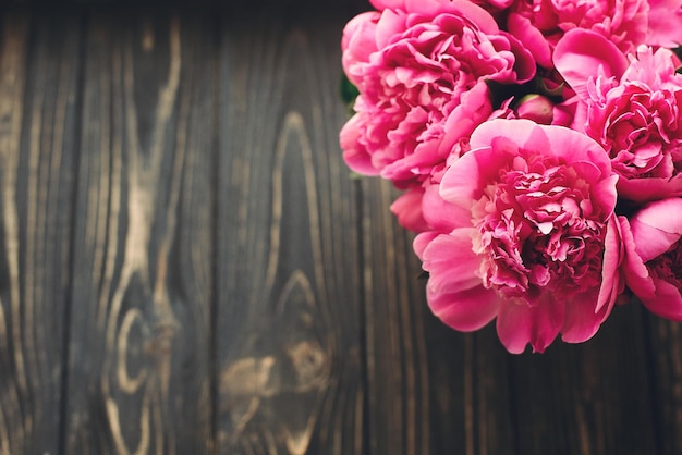 Photo bouquet de pivoines roses sur l'espace de vue de dessus de fond en bois foncé rustique pour le texte maquette de carte de voeux floral plat poser concept de fête des mères heureux image florale de fleurs roses