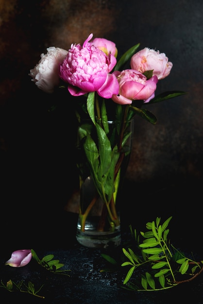 Un bouquet de pivoines roses se dresse sur un fond sombre. Image créative pour papier peint et intérieur.