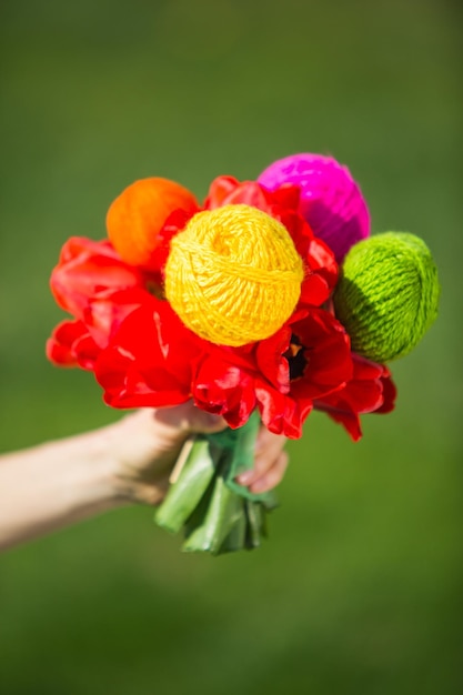 bouquet de printemps dans une main avec des tulipes et des boules de tricots