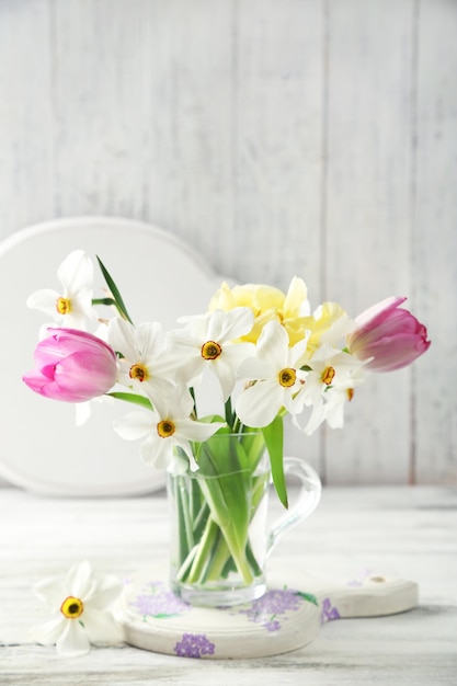 Bouquet de printemps dans une tasse en verre sur fond de bois de couleur