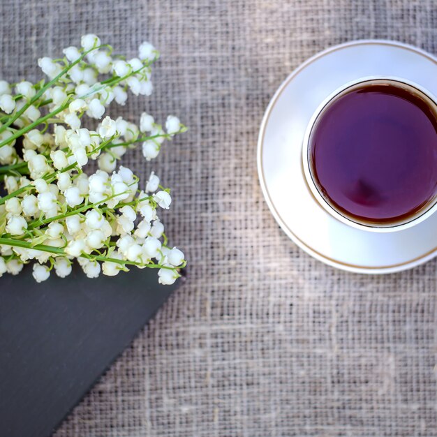 Bouquet de printemps de muguets sur le livre et une tasse de thé