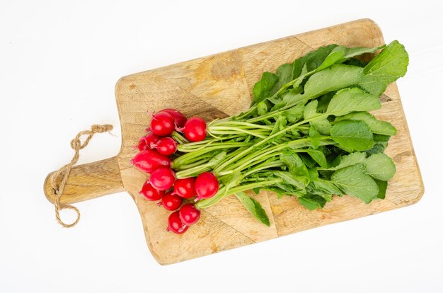 Bouquet de radis frais sur planche à découper en bois de cuisine. Studio photo.