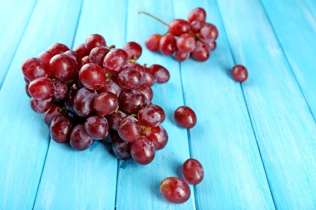 Bouquet de raisin rouge avec feuille sur fond de bois bleu