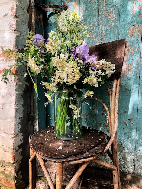 Bouquet romantique avec des inflorescences de viburnum, des iris, des alliums et des inflorescences de raifort dans un style rétro dans la cour sur fond d'une vieille porte bleue