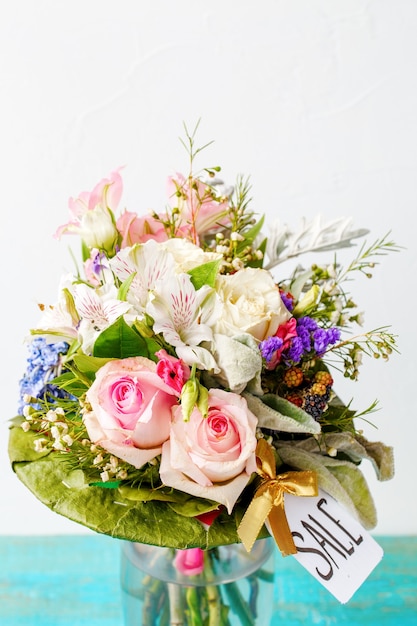 Bouquet romantique de roses roses, lys, feuilles vertes sur table bleue en bois