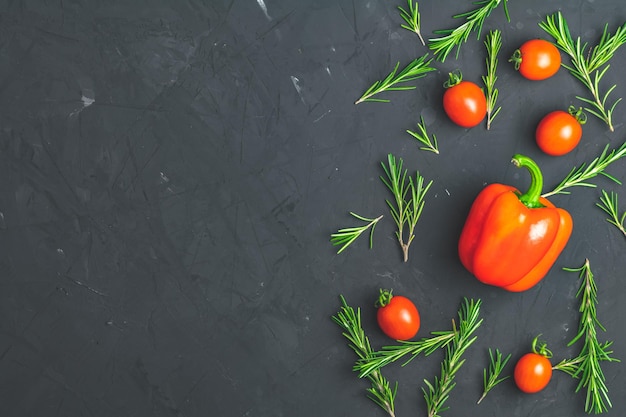 Bouquet de romarin poivre cru et tomates cerises sur fond de surface texturée en béton de pierre noire Vue de dessus avec espace de copie pour votre texte