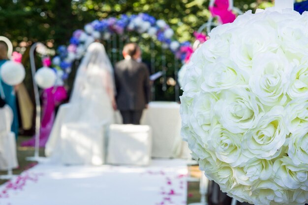 Photo bouquet de roses blanches contre un couple de jeunes mariés