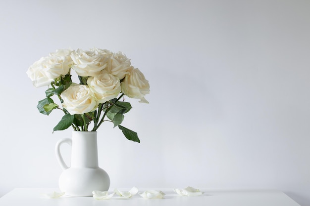 bouquet de roses blanches dans une cruche sur fond blanc