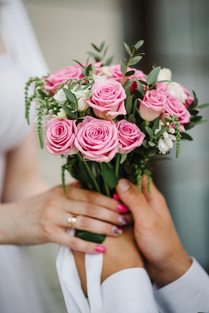 Bouquet de roses blanches et roses dans les mains de la mariée Couple de jeunes mariés Marié et mariée ensemble Couple de mariage parfait tenant un bouquet de fleurs de luxe Gros plan
