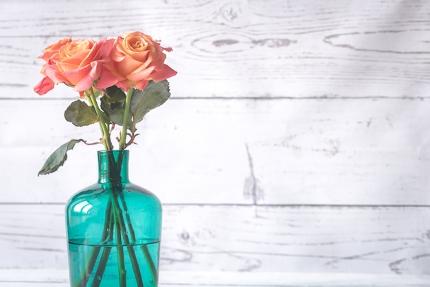 Bouquet de roses dans le vase sur la surface en bois