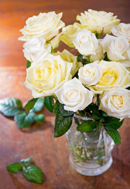 Bouquet de roses en fleurs dans un vase sur un fond en bois