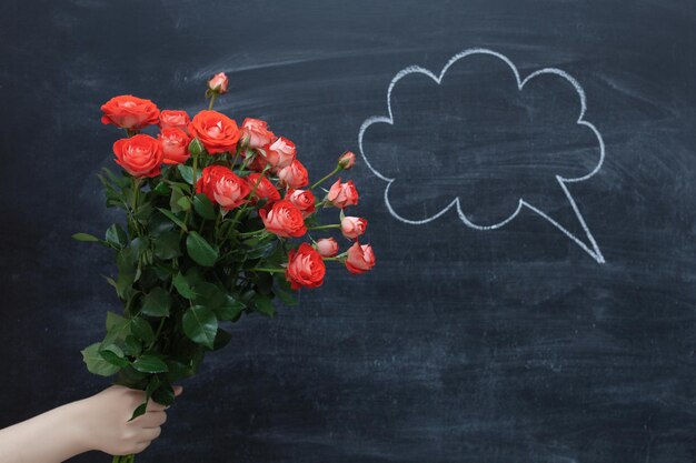 Bouquet de roses sur un fond de tableau. Un nuage de parole dessiné à la craie.