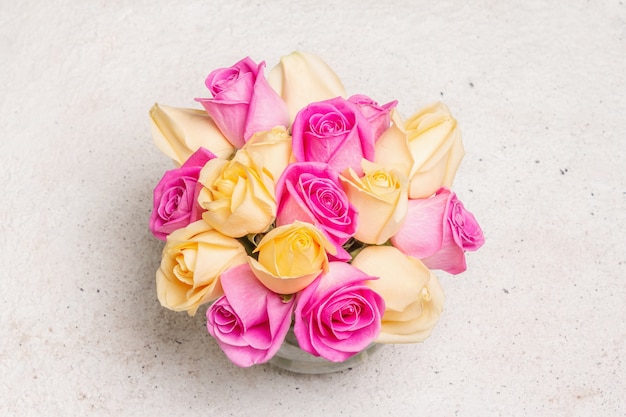 Bouquet de roses multicolores fraîches dans un vase. Le concept festif pour les mariages, les anniversaires, le 8 mars, la fête des mères ou la Saint-Valentin. Carte de voeux, fond clair