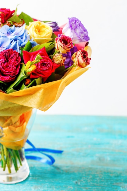 Bouquet de roses multicolores sur table en bois bleu