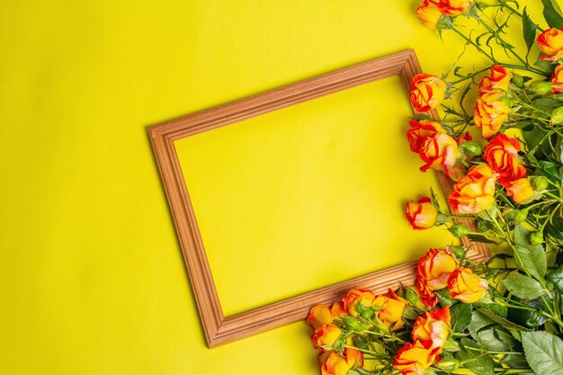 Bouquet de roses orange vif avec cadre en bois sur fond jaune vif