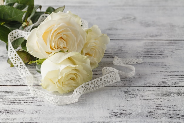 Bouquet de roses orné de dentelle sur fond de bois blanc