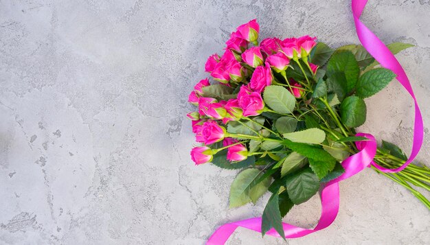 Bouquet de roses rose vif sur un fond de béton gris