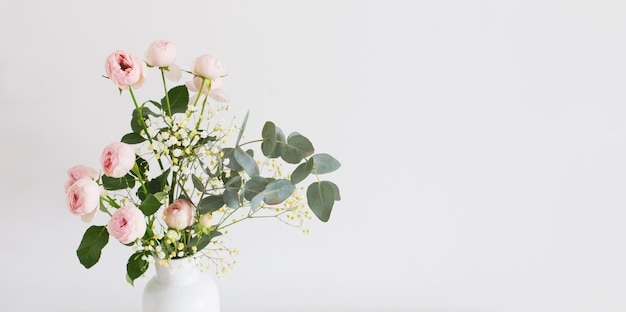 Bouquet de roses roses dans un vase blanc en céramique sur fond blanc