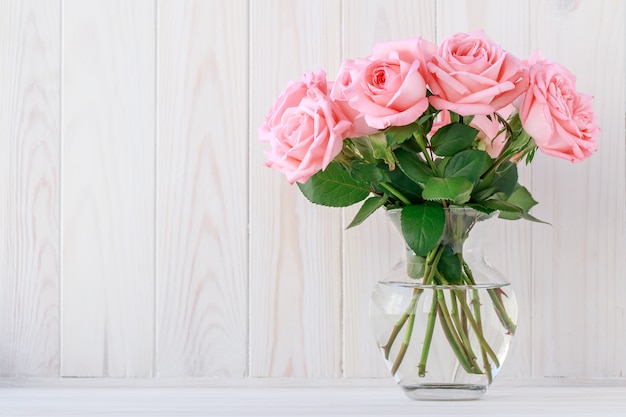 Bouquet de roses roses dans un vase en verre, fond floral.