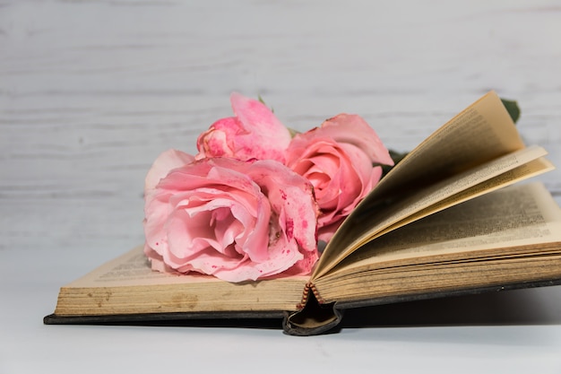 Un bouquet de roses roses et de livres sur bois rustique