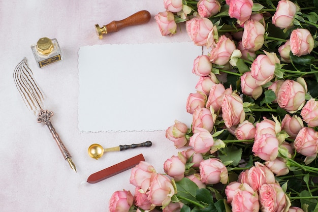 bouquet de roses roses, stylo plume, encrier, sceau et cire