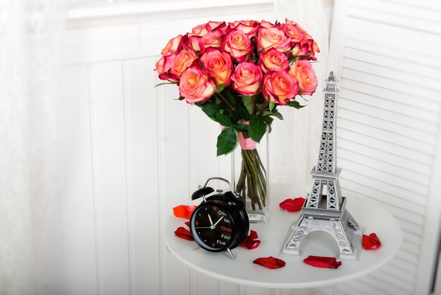 un bouquet de roses roses sur une table avec une tour Eiffel miniature