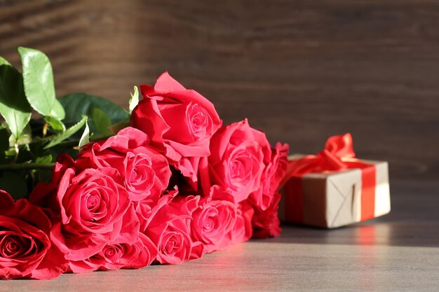 Photo bouquet de roses rouges et boîtes de cadeaux sur un fond sombre