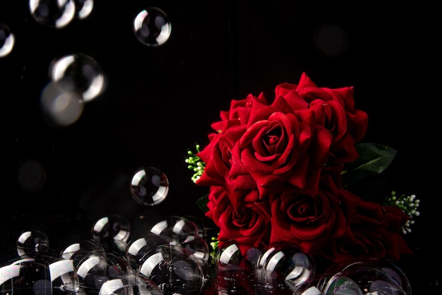 Bouquet de roses rouges, bulles de savon sur fond noir, mise au point sélective.