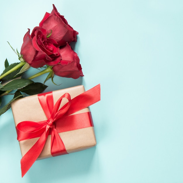 Bouquet de roses rouges et cadeau sur bleu. Carte de valentine Espace de copie.