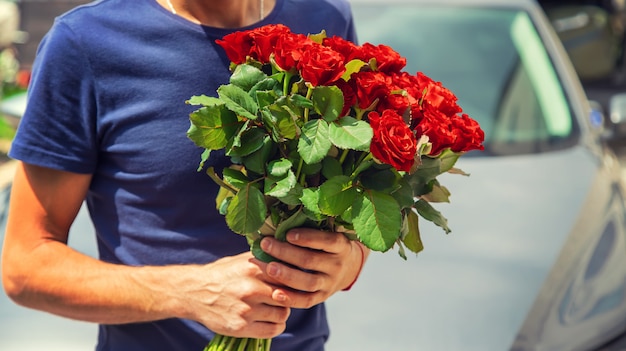 Un bouquet de roses rouges dans les mains d'un homme.