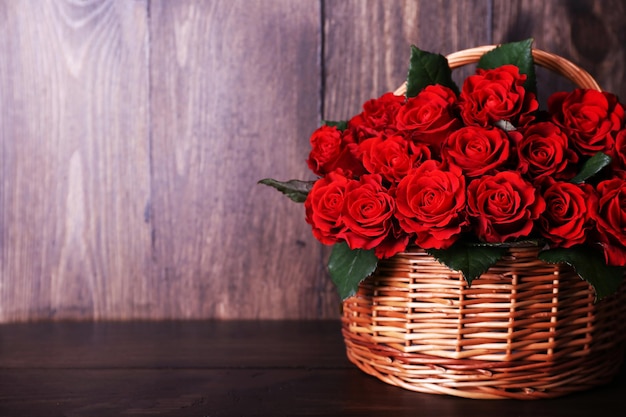 Bouquet de roses rouges dans le panier sur fond de bois