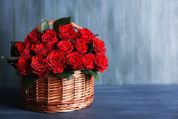 Bouquet de roses rouges dans le panier sur fond de bois