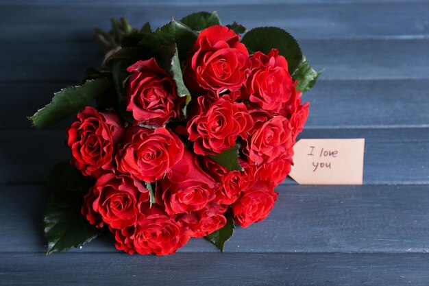 Bouquet de roses rouges avec étiquette sur fond de bois