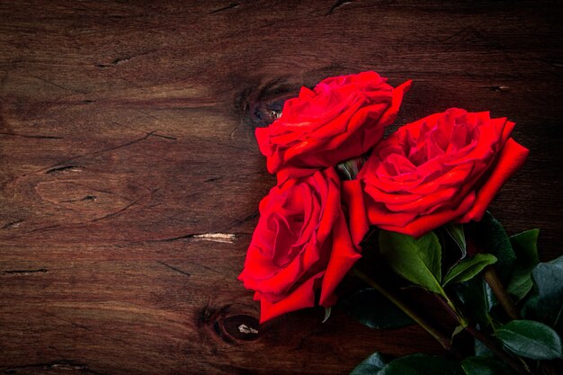 Bouquet de roses rouges sur un fond en bois texturé, espace libre pour le texte