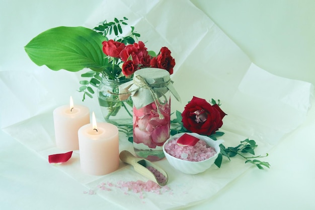Bouquet de roses rouges fraîches, eau avec pétales de rose roses, sel de mer et bougies allumées
