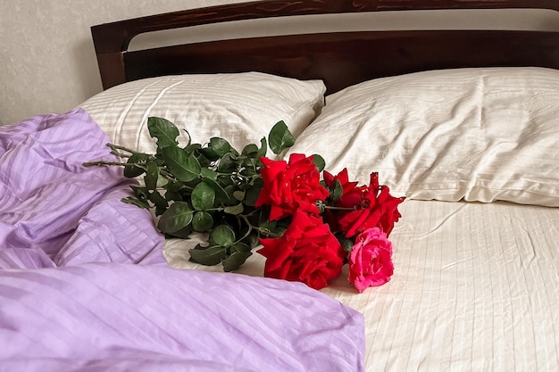 Un bouquet de roses rouges se trouve sur le linge de lit whitelilac Minimalisme esthétique Carte de voeux avec bonjour