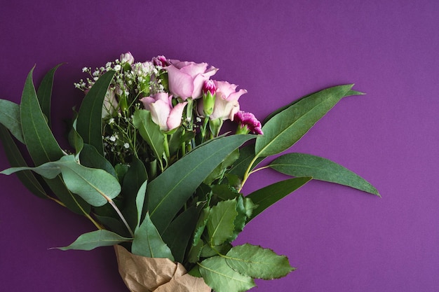 Bouquet de roses violettes et d'eucalyptus sur fond violet Espace de copie Vue de dessus