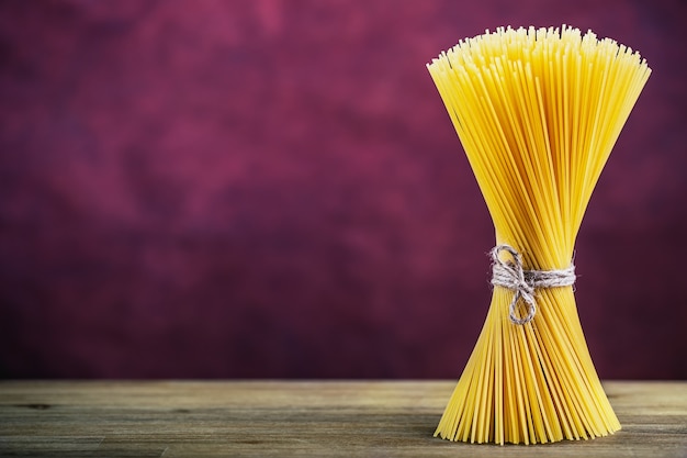 Bouquet de spaghettis sur table en bois - fond violet.