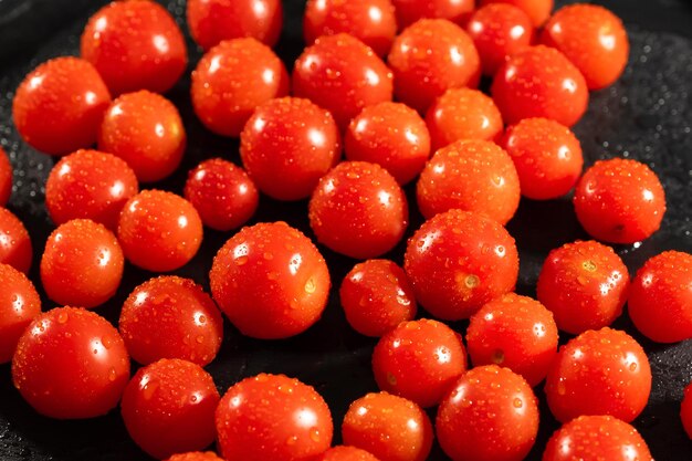 Bouquet de tomates rouges avec des gouttes d'eau sur une table de cuisine noire