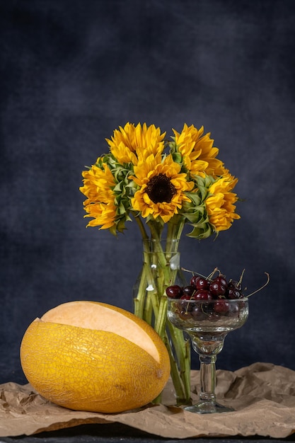 Un bouquet de tournesols d'automne dans un vase en verre sur du papier kraft. Vase melon et cerise haute