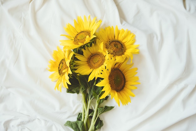 Bouquet de tournesols jaunes authentiques candides sur fond de tissu blanc avec bouquet de