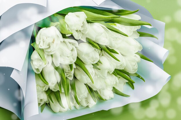 Un bouquet de tulipes blanches sur un fond vert pastel fleurissant concept festif